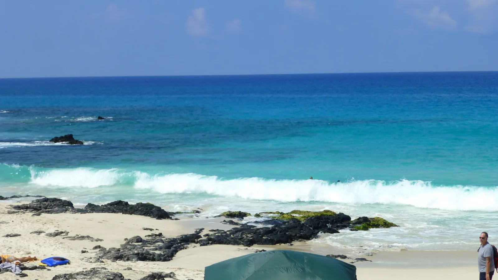 Hawaii – Türkisblaue Wellen an felsigem Sandstrand